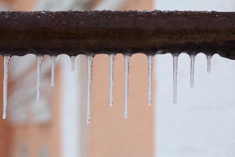 What Should I Do to Fix Frozen Pipes? Photo icicles hanging off of a frozen water pipe.