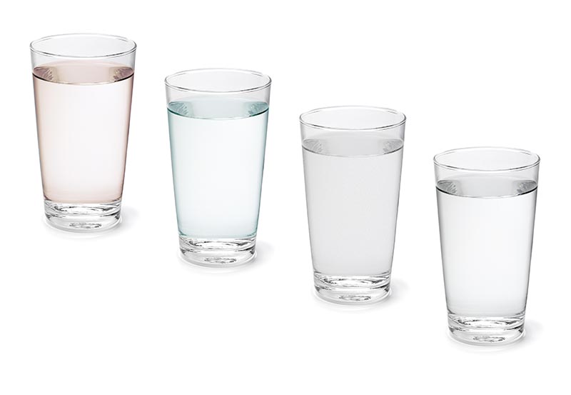 A clear drinking glasses filled with liquids, arranged diagonally against a plain white background.